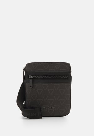 Sac bandoulière noir en matériau texturé avec un motif répétitif de logo, fermeture zippée et sangle en tissu ajustable.