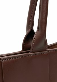 Smeškanja smešna kožna torba s dva čvrsta ručka, koja se odlikuje čistim linijama, minimalnim detaljima šivanja i glatkom teksturom.