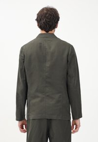 Giacca in cotone verde oliva con un design semplice, maniche lunghe e una texture morbida. Presenta una linea dritta e dettagli di cucitura visibili.