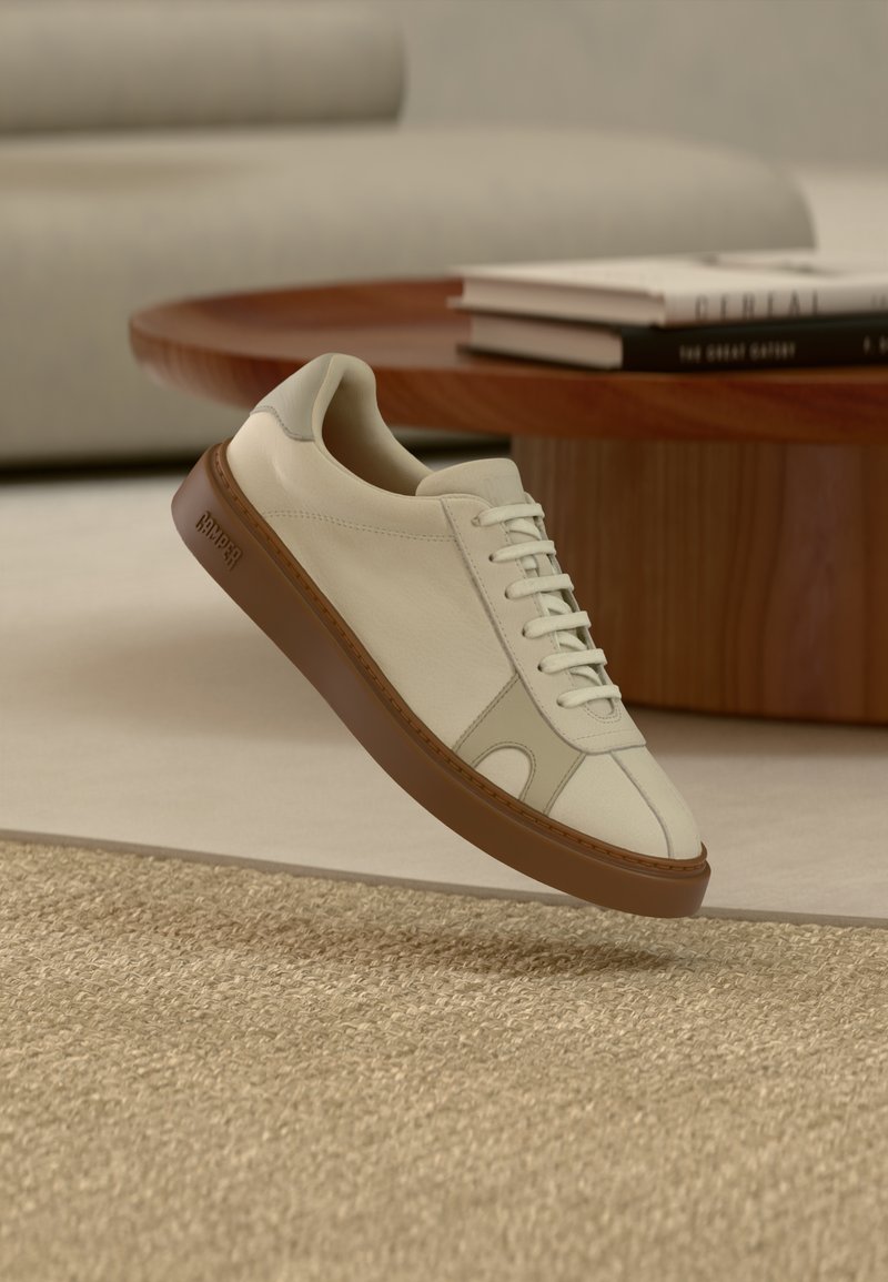 Το αθλητικό παπούτσι διαθέτει επάνω μέρος από κρέμα δέρμα, ελαφριά ραφή και καφέ λαστιχένια σόλα. Έχει στρογγυλεμένη μύτη και κλασικό σχέδιο κορδονιών.