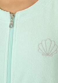 Giacca verde menta con zip, dal texture morbido, caratterizzata da un ricamo in lamina d'argento sulla parte anteriore e una chiusura con zip liscia.