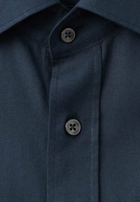 Camisa azul marino con cuello estándar, un solo botón en el cuello y una tela texturizada con un patrón de tejido sutil.