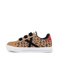 Zapatillas de estampado de leopardo con parte superior de ante color canela, correas de Velcro negras y una suela de goma blanca con un acento rojo en el talón.