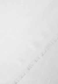 Tissu blanc affichant un motif géométrique subtil, avec une texture lisse et des bords frangés. Doux et léger, idéal pour le drapage.