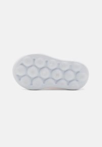 Sohle eines Turnschuhs mit einer strukturierten weißen Gummioberfläche, die kreisförmige Muster und eine glatte Kontur aufweist, entworfen für Traktion und Komfort.