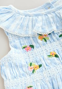 Ljusblå smockad klänning med en volangkrage och flerfärgad blommig broderi. Strukturerad tyg med subtila vita ränder.