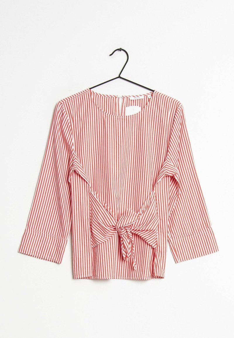Červeno-bíle pruhovaná blůza s tříčtvrtečními rukávy, kulatým výstřihem a detailem uvázání vpředu, zavěšená na černém ramínku.