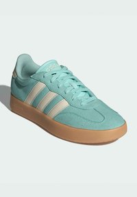 Aqua suede sneaker with beige stripes, rubber gum sole, and lace-up design. Features a padded collar and textured upper for grip.