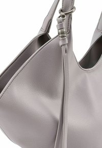 Grijze leren handtas met een gestructureerd oppervlak, voorzien van een enkele schouderriem en een decoratief metalen accent bij het bevestigingspunt.