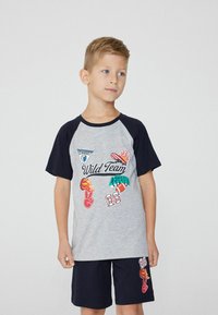 Šedý a námořnický dvoudílný set, top s krátkým rukávem a grafikou "Divoký tým" a šortky s akcenty. Materiál: kombinace bavlny, casual střih, pohodlná textura.