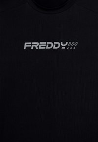 Tee-shirt de sport noir avec un tissu texturé et un logo "FREDDY" argenté en évidence sur le devant. Encolure ronde avec des manches courtes.