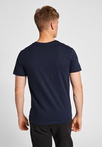 Marinblå bomullst-shirt, kort ärm, rundad halsringning, avslappnad passform, enfärgad textur, inga synliga mönster eller accenter, visad från baksidan.