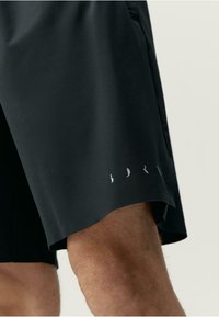 Fekete sportnadrág könnyű anyagból, finom logónyomattal az alján és kényelmes rugalmas derékkal.