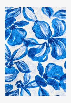 Motif floral bleu avec de grandes pétales et feuilles sur un fond de tissu blanc texturé.