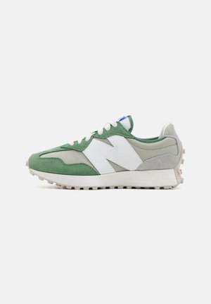 Green and white New Balance sneaker with suede and mesh panels, white laces, and textured sole, shown from the side on a plain background.