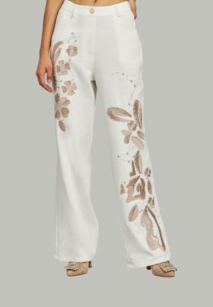 Pantaloni bianchi a gamba larga con intricato ricamo floreale beige su ogni lato, dotati di chiusura a bottone e tasche frontali.