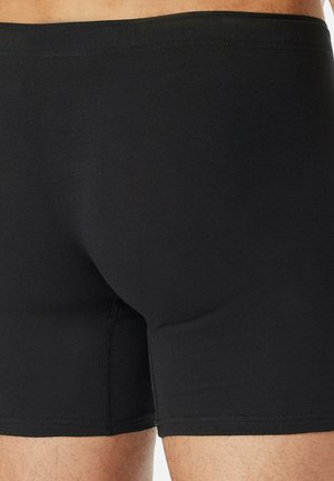 Schwarze Baumwoll-Boxershorts mit weicher Textur, elastischem Bund und körpernaher Passform. Mit nahtlosen Seiten und minimalen Nähten.