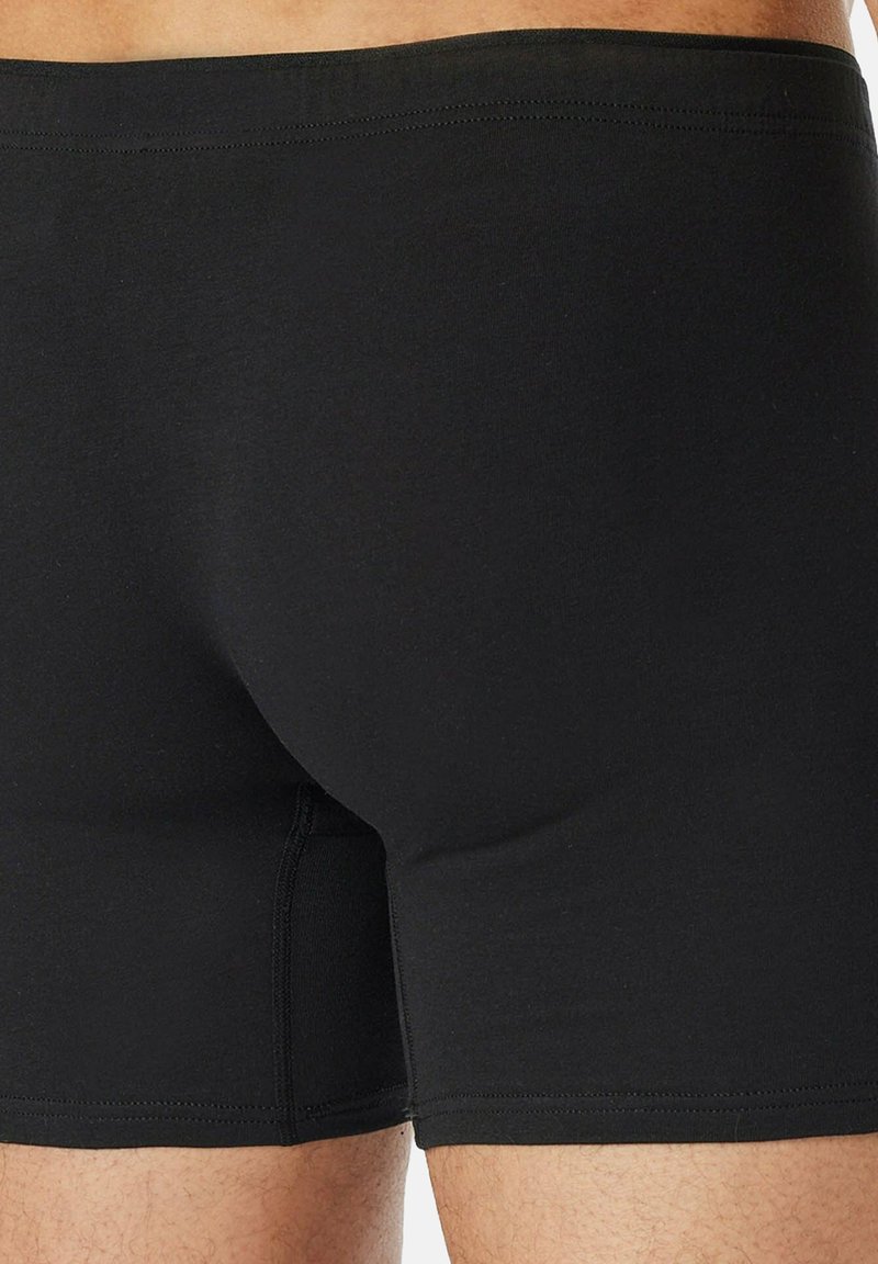 Schwarze Baumwoll-Boxershorts mit weicher Textur, elastischem Bund und körpernaher Passform. Mit nahtlosen Seiten und minimalen Nähten.