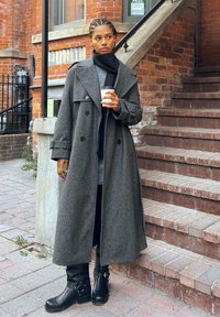 Szary płaszcz z wełny z podwójnym zapięciem i dużym kołnierzem, poł�ączony z czarnymi skórzanymi kozakiem za kostkę z metalowymi akcentami.