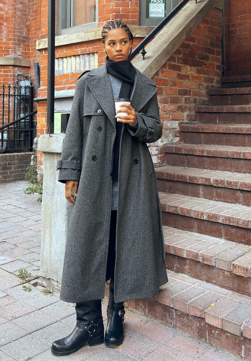 Szary płaszcz z wełny z podwójnym zapięciem i dużym kołnierzem, połączony z czarnymi skórzanymi kozakiem za kostkę z metalowymi akcentami.