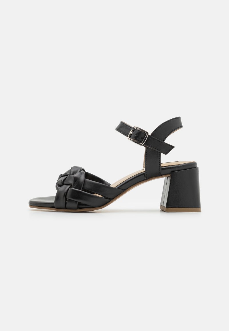 Sandales à talons noirs avec un design de lanières tissées, dotées d'un bout carré, d'une sangle à la cheville avec boucle, et d'un talon carré robuste.