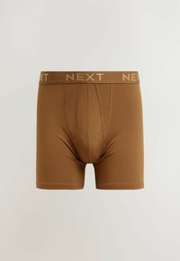 Barna boxer alsónemű rugalmas anyagból, texturált derékkal, amelyen arany "NEXT" logó található, és testhez álló fazonú, füles nyitással.