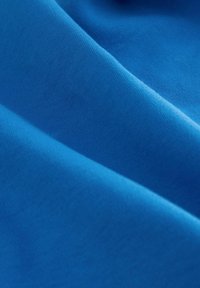 Primo piano di un tessuto blu morbido e liscio con sottili pieghe che mostrano dettagliati texture e motivo di tessitura.