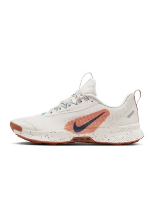 Biały but do biegania Nike Trail z granatowym znakiem Swoosh w pomarańczowej siateczce, białą nakrapianą podeszwą i brązową podeszwą zewnętrzną, pokazany z profilu.