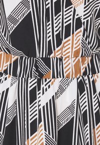 Svart och vitt mönstrat tyg med djärva geometriska linjer och former, med inslag av brunt. Slät textur och veckad design.