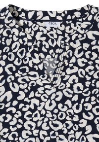 Blouse marine à imprimé léopard blanc, encolure en V et étiquette de la marque "Cecil" à l'intérieur du col.