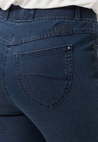 Jeans in denim scuro con vita alta e design classico a cinque tasche, con cuciture a contrasto e una patch in pelle con il marchio sul retro.