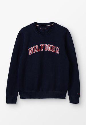 Granatowy sweter dzianinowy z okrągłym dekoltem i ściągaczami na rękawach. Czerwono-biała nazwa "HILFIGER" wyraźnie widoczna na wysokości klatki piersiowej.