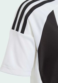 Weißes und schwarzes Sporttrikot mit einem strukturierten oberen Panel, das drei schwarze Streifen auf der Schulter und einen glatten Kragen aufweist.
