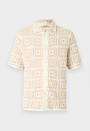 Short-sleeve cream button-up shirt with beige geometric square pattern and a pointed collar.