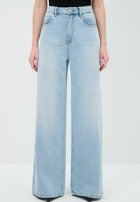 Jeans de pierna ancha azul claro hechos de denim, diseño de cintura alta, con bolsillos frontales y un solo botón de tono dorado en la cintura.