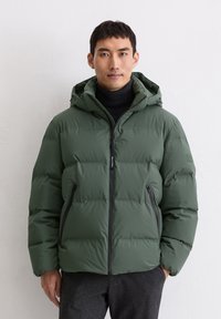 Veste puffer verte avec capuche, design matelassé, fermeture éclair à l'avant et deux poches latérales. Conçue en matériau lisse et résistant à l'eau.