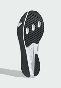 Fekete-fehér sportcipő talp, texturált gumialappal, jól meghatározott barázdákkal, három kör alakú kivágással és "ADIZERO" márkázással.