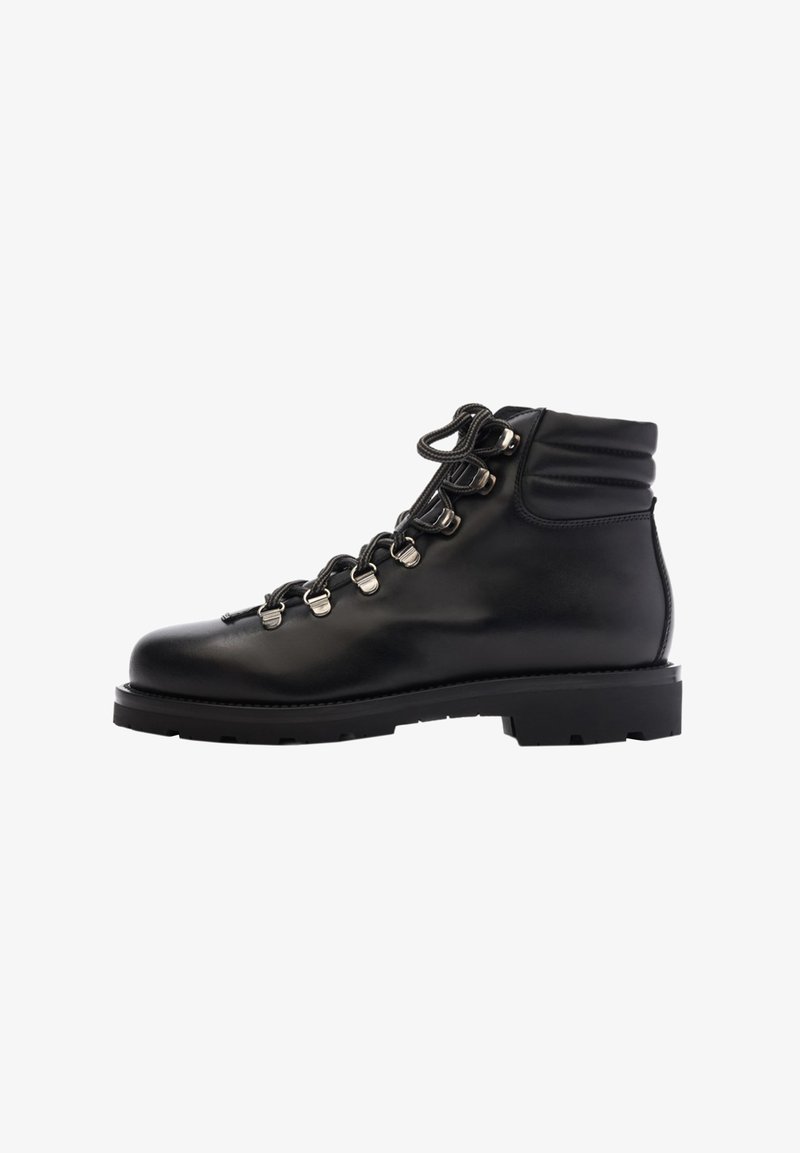 Botín de cuero negro hasta el tobillo con punta redonda, cuello acolchado, suela resistente y ojales de metal. Presenta cordones para un ajuste seguro.
