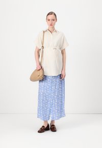Blusa a maniche corte a righe con cintura a fiocco; gonna azzurra chiara con motivo floreale bianco; scarpe marroni; borsa a tracolla beige.