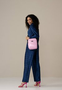 Blauwe geribbelde jumpsuit, roze glanzende vierkante tas met een gestructureerd oppervlak en heldere roze high-heeled sandalen. Eenvoudig en modern ontwerp.