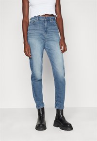 Džínové kalhoty s vysokým pasem v modré barvě se zesvětleným vínem, rovný střih, pět kapes, spojené s černými botami na podpatku.