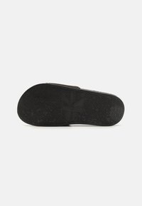 Suola di scarpa da ginnastica nera in gomma con motivi di grip testurizzati e logo Calvin Klein. Il design è piatto e snodato.