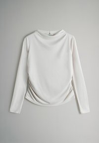 Długo rękawowa biała bluzka z gładkiego materiału, z okrągłym dekoltem i marszczeniami po bokach.