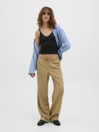 Svart, ribbet tanktopp, oversized lyseblå denimskjorte, løse beige bukser og svarte slip-on sko. Minimalistisk design, avslappet utseende.