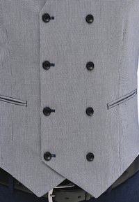 Dwurzędowa kamizelka w czarno-białym wzorze w zęby psa. Oferuje sześć czarnych guzików, płaskie kieszenie oraz dopasowany krój z ostrymi krawędziami.