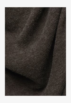 Hnědá pletená látka s jemnou texturou, která má ribbovaný vzor a mírný lesk, vykazuje záhyby a sklady.