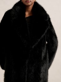 Svart fuskpälsjacka med bred krage, som har en mjuk, texturerad yta och hela ärmar, som draperar sig elegant runt axlarna.