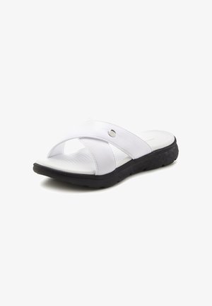 White slide sandals with crossed synthetic straps, a silver accent, and a textured white footbed. Black rubber sole with patterned tread.