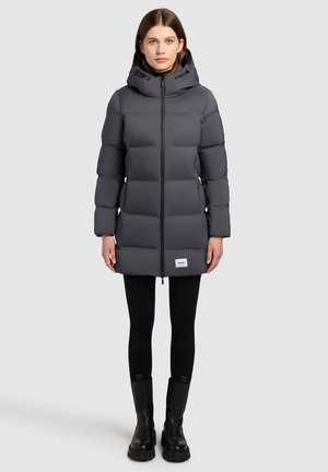 Veste doudoune grise avec capuche, fermeture éclair à l'avant et poignets élastiques. Design longueur genoux avec texture matelassée et patch logo à l'ourlet.