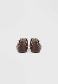 Ζευγάρι χαμηλά, καφέ και ροζ αθλητικά παπούτσια casual, με θέα από πίσω σε απλό ανοιχτό γκρι φόντο.